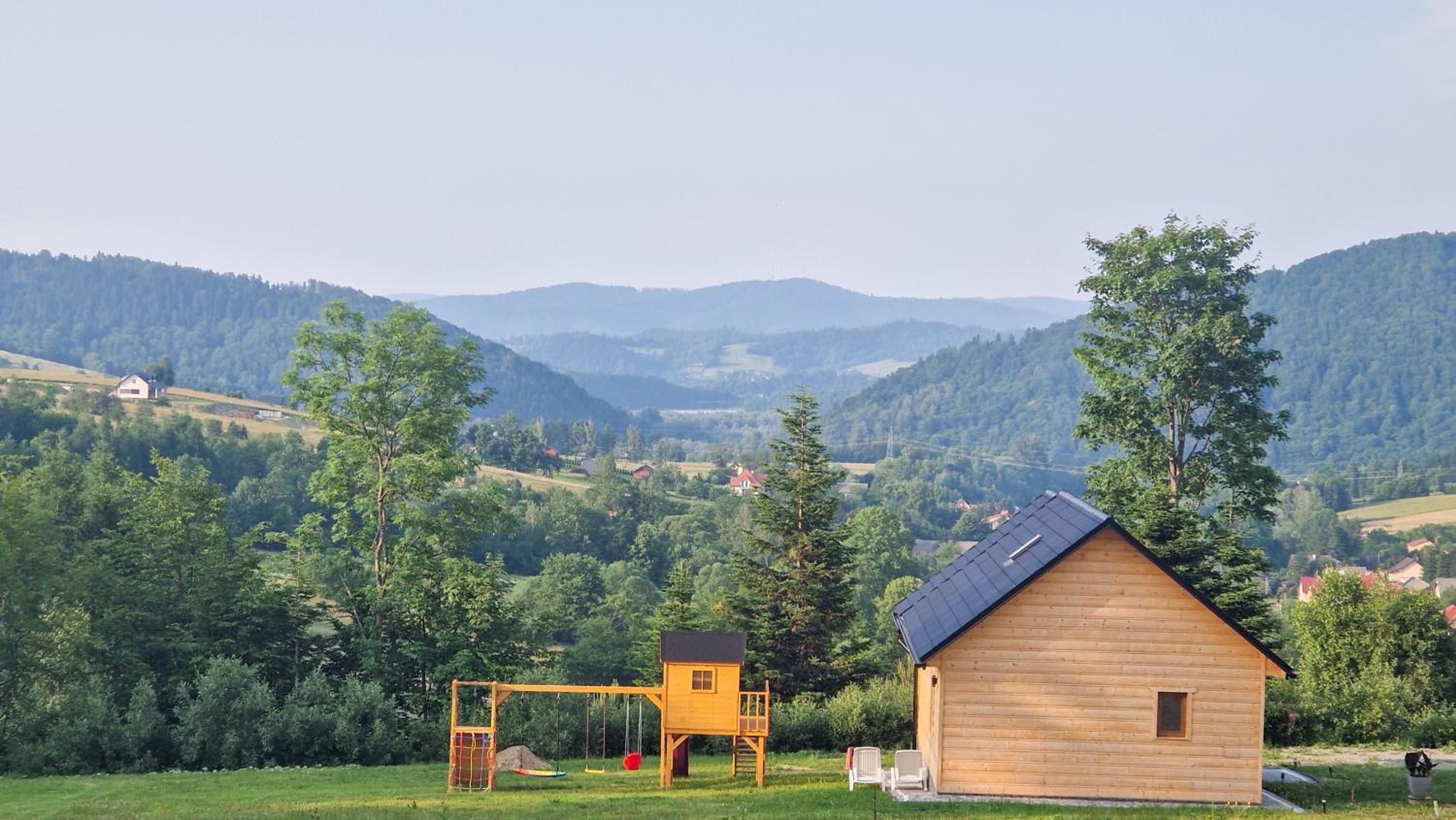 Domek Fraseryja i plac zabaw na tle zalesionych gór